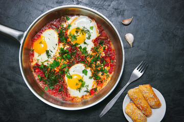 Tasty and healthy shakshuka, Middle Eastern omelet in frying pan. Delicious scrambled eggs cooked in spicy tomato pepper sauce. Top view