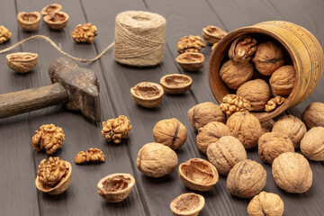 Walnuts are scattered from a wooden bowl on table.