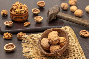 Whole walnuts in coconut shells on burlap cloth. Walnut kernels in wooden bowl.