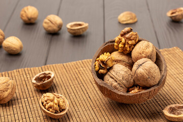 Whole and cracked walnuts in coconut shells on napkin of thin wooden sticks.