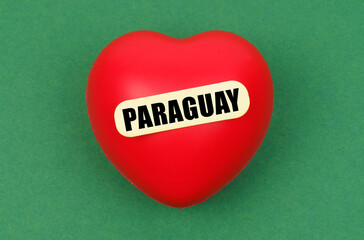 On a green surface lies a red heart with the inscription - Paraguay