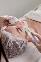 Cosmetologist, beautician making facial treatment with ultrasonic spatula to young woman,face skin scrubber treatment with ultrasonic spatula,facial cleansing procedure in beauty salon