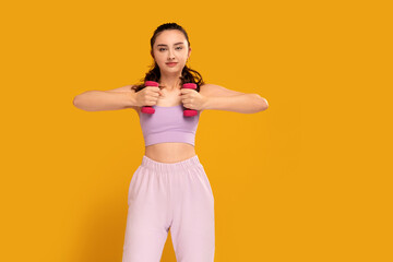Young fitness woman in fashionable sporty clothes posing on the yellow studio background. Healthy lifestyle concept