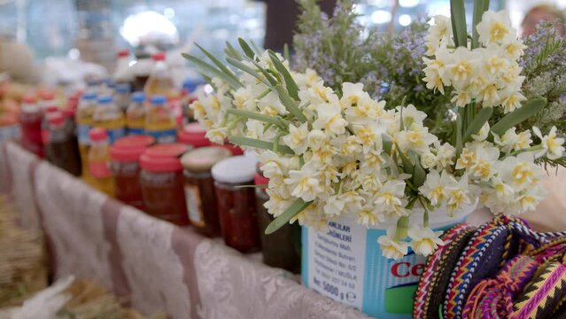 Open air market. People in bazaar choose products. Flowers and honey on the counter. Fethiye, Turkiye- January 05, 2023.