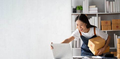Startup small business entrepreneur of freelance Asian woman using a laptop with box Cheerful success online marketing packaging box and delivery SME idea concept. © PaeGAG