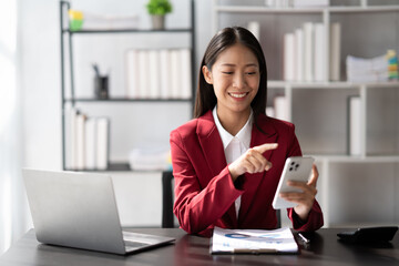 Smiling businesswoman using phone in office. Small business entrepreneur using her mobile phone and smiling while working.