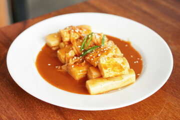 Tteok-bokki with white sesame served on white plate. Tteokbokki, simmered rice cake is a popular Korean food.