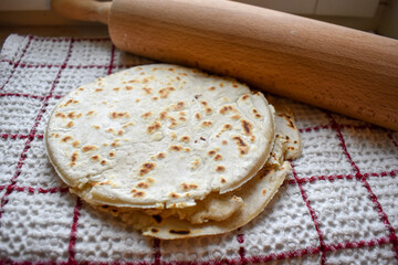 Stack of thin flatbread tortillas on a wooden serving board