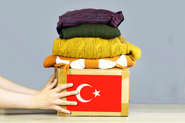 closeup woman hands holding carton box with used clothes for donation and turkey flag Earthquake,...