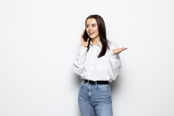 Portrait of a smiling young woman talking on mobile phone isolated over white background