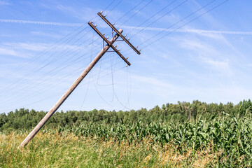 an old rickety pole with a cable on the field. the cable is cut and loose