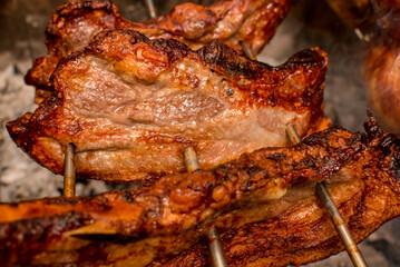 Several pieces of Liempo, or pork belly skewered on a spit and roasted on an oven at a roadside restaurant.