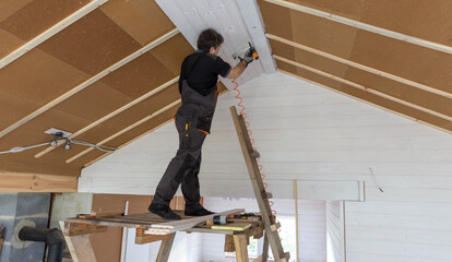 Construction worker thermally insulating eco wooden frame house.