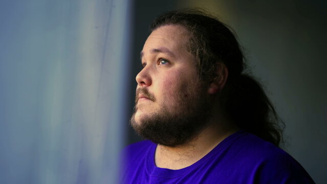 One Contemplative Casual Man Standing By Window Looking Out. Calm Meditative Person At Home With Thoughtful Expression