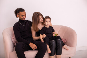 A beautiful young family with a young son, sitting on a pink sofa in a bright living room