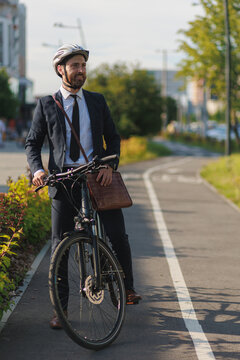 Elegant man in business suit cycling in town at daytime.