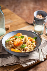 Millet groats dessert with caramelised apricots, almonds and mint leaves. Breakfast bowl.
