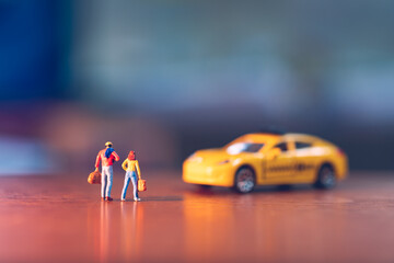 Miniature people, man and woman waiting taxi using as tourism concept