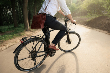 Fototapeta na wymiar Male worker in smart casual cycling on bike along city park.