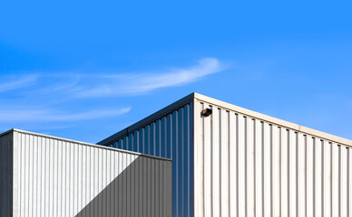 Fototapeta na wymiar Low angle view of corrugated steel Warehouse next to Industrial Building against blue sky Background