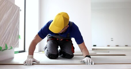 Worker laying vinyl or laminate flooring renovating home or office