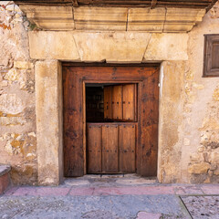 Fototapeta na wymiar Old wooden door that opens in two parts in the stone houses of the medieval village of Pedraza, Segovia.