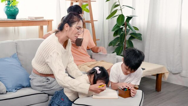 4K, Beautiful Asian pregnant mother, she draw and paint with she daughter and son, It is a leisure activity on weekends children, father sitting in back looked at three of them, and smiled happily.