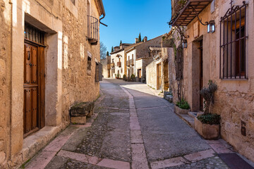 Fototapeta na wymiar Narrow alley with stone houses and wooden gates in the picturesque medieval village of Pedraza, Segovia, Spain.
