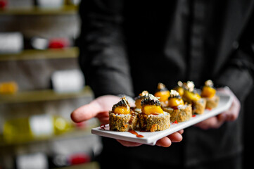 Man chef hand holding a plate full of sushi 