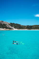 Vertical photo of a couple snorkelling in the aqua blue water of Blue Haven in Esperance, Western Australia