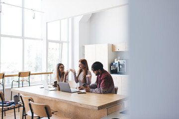 Cheerful colleagues having conversation while working on project in office