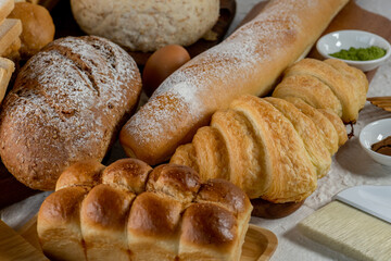 Mix bread kind of cereal bakery yeast white bread, pasties, buns, rye pretzel sourdough leavened tortilla and croissant on old wooden background.