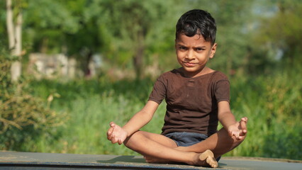 Naklejka na ściany i meble Child doing exercise on platform outdoors. Healthy lifestyle. Yoga boy