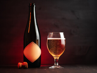 Bottle and Glass of cider on a dark wooden background