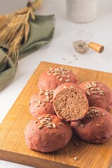 Rye and wheat flour bread buns with beetroot puree and sunflower seeds on a wooden board on a light...