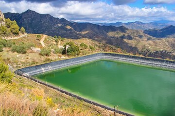 Water reservoir in the mountain agricultural landscape, Andalusia, Spain. Watering for fields,...