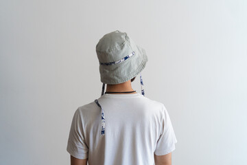 Product photo of a bucket hat being worn by a young man on his back on a white background.