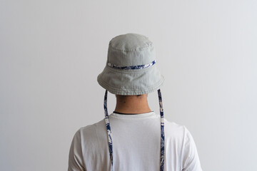 A bucket hat with a blue cord being modeled by a young man on his back. Product photo.