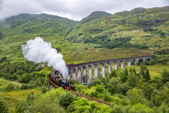 Glenfinnan railway viaduct in Scotland with the Jacobite steam train passing by © lapas77