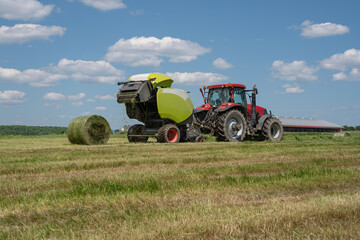 Baling hay baling or pressing hay pressing with round hay baler in the fields. 