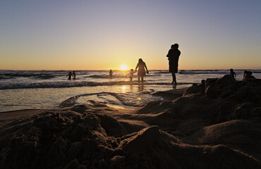 niños y sus padres corriendo hacia el mar al atardecer