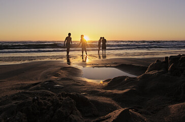 niños y sus padres corriendo hacia el mar al atardecer