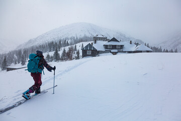 Fototapeta na wymiar A skier hiker approaches a mountain house in a snow blizzard
