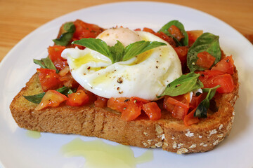Plate of Tasty and Healthy Fresh Tomato and Basil Toast Topped with Poached Egg
