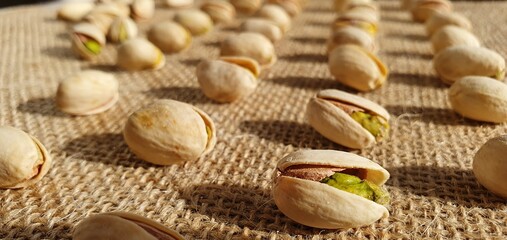 Delicious pistachios on burlap fabric. Pistachio nuts close-up. Salted pistachios. Pistachios on the table. 