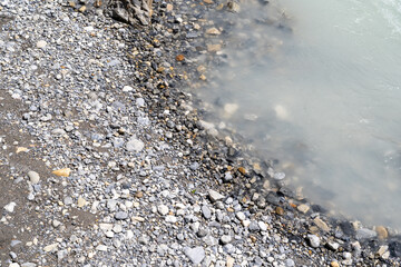 The milky silt water from glacial runoff in the Canadian Rockies, close up of rocks and river water