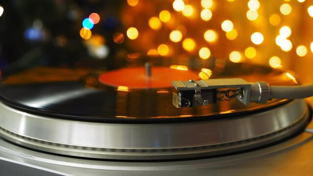 Retro turntable with vinyl records of Christmas lights spins the record. Medium plan