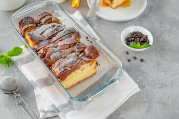 Homemade bread pudding with chocolate chips on a gray concrete background. Selective focus, copy space.