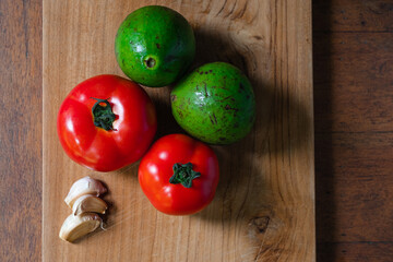Vegetables - tomato and avocado, on a wooden table, top view.