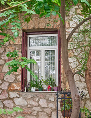 Fototapeta na wymiar A window with potted Aloe vera plants on dak stonewall. Travel to Athens, Greece.